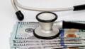 Photo of a stethoscope and cash money, representing concepts of the healthcare, health insurance and medical bills.