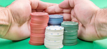 Man hand raking poker chips on green poker table.