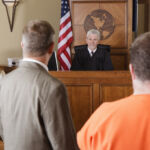 A lawyer standing with his client before the judge in a criminal trial.