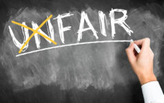 hand writes the word unfair and crosses the "un" changing the word to fair on a blackboard