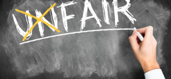 hand writes the word unfair and crosses the "un" changing the word to fair on a blackboard