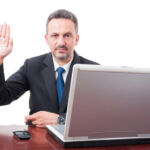 Serious male manager doing a false testimony and holding fingers crossed isolated on white background