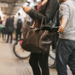 Thief stealing wallet from purse of a woman using mobile phone at the subway station. Pickpocketing at subway station
