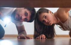 The man and a woman with a flashlight looking under the bed