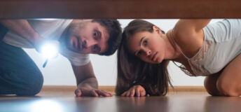 The man and a woman with a flashlight looking under the bed