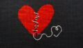 Two halves heart embroidered red thread on black fabric. Two halves heart sewn with black thread.