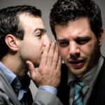 image of a young professional whispering to another