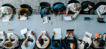 Top view of diverse business group in office meeting, collaborating and discussing around a large table.