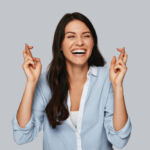 Compliance committee recommended for SEC Attractive young woman crossing fingers and smiling while standing against grey background