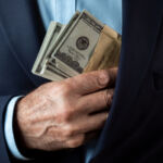 Contradictory disclosures cost $19M A man in a suit holding an envelope with cash, symbolizing bribery, corruption, or financial transactions in secrecy.