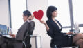 Work romance between two business people holding a heart