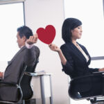 Work romance between two business people holding a heart
