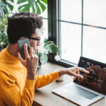 Treasury extends comment period on GENIUS Act implementation Young man at home office. He is sitting near window and using smart phone while working on laptop.