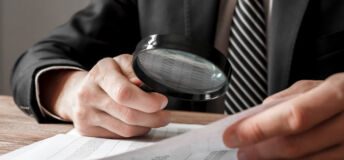 Businessman holding magnifying glass zoom and analyzing financial indicators