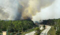 Aerial view of fire department firetrucks extinguishing wildfire burning severely in Florida jungle woods. Emergency service firemen trying to put down flames in forest.