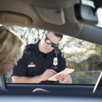 Police officer giving woman a traffic ticket. (20s).