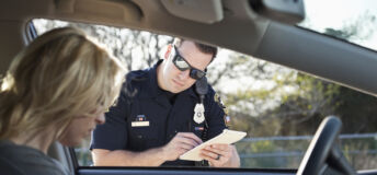 Police officer giving woman a traffic ticket. (20s).