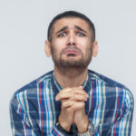 Please help me! Bearded man need a help. Isolated on gray background, studio shot
