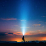A person holding a flashlight under the starry sky