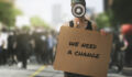 public protest and riots in the city streets. woman with megaphone and cardboard poster in hands on protesters crowd background. democracy concept