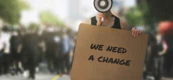 public protest and riots in the city streets. woman with megaphone and cardboard poster in hands on protesters crowd background. democracy concept