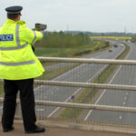 A British Police officer operating a hand held speed gun