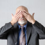 Business man covering his eyes with hands in studio with white background