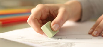 Close up of woman hands using rubber erasing pencil drawing on a desk at home