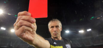 Portrait of referee showing red card during football match.