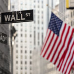 FINRA action on trade reporting, arbitrators Wall street sign in New York City with American flags and New York Stock Exchange in background.