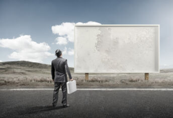 SEC releases two new marketing FAQs A business man standing and staring at a blank billboard advertisement.
