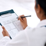 Cropped shot of an unrecognizable female doctor writing on a clipboard while working in her office