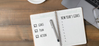 Hand man writing New year's goals on note paper with coffee and laptop, Business motivation and inspiration conceptual