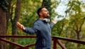 Mid adult man with arms outstretched outdoors