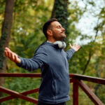 Mid adult man with arms outstretched outdoors