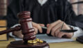 Divorce concept. Law and Justice background. Judge gavel on with two golden wedding rings.