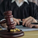 Divorce concept. Law and Justice background. Judge gavel on with two golden wedding rings.