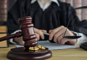 Divorce concept. Law and Justice background. Judge gavel on with two golden wedding rings.