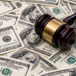 Litigation funding goes mainstream wooden hammer on dollar. close up