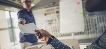 Unrecognizable man taking notepad from his female colleague in the office. Focus is on his hand and note pad.