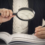 Corruption audit concept. Inspector using magnifying glass for inspect budget corruption