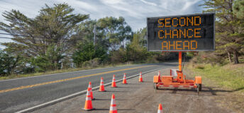 SECOND CHANCE AHEAD: This is a photograph of a mobile roadside sign parked on highway one in northern California. It is a trailer and powered by batteries and provides information and warnings for drivers by displaying words on a large panel display.