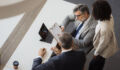 Three business people discussing a document during a corporate meeting