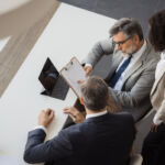 Three business people discussing a document during a corporate meeting