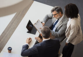 Three business people discussing a document during a corporate meeting