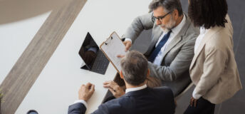 Three business people discussing a document during a corporate meeting