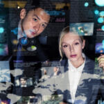 Two business persons in front of futuristic display. Graphical User Interface(GUI). Head up Display(HUD). Internet of things.