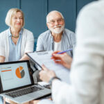 Happy senior couple during the meeting with agent or financial consultant, signing some agreement in the comfortable office