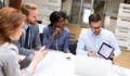 Group of business people is working on new business strategy with a financial analyst while analyzing financial chart during meeting in the office.
