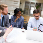 Group of business people is working on new business strategy with a financial analyst while analyzing financial chart during meeting in the office.